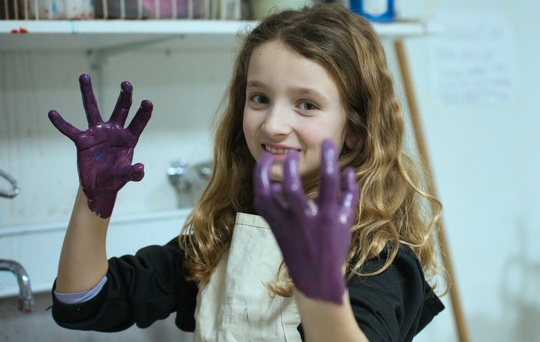 Pige fra billedkunst med maling på hænderne