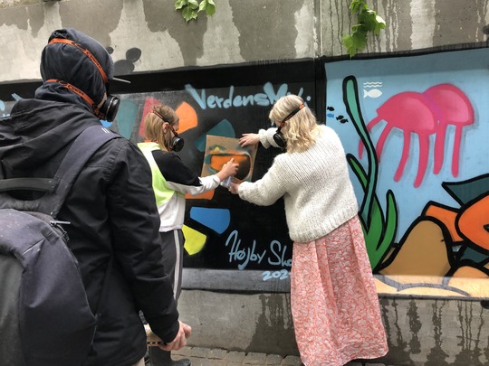 Børn- og ungerådmand Susanne Crawley Larsen spraymaler graffiti sammen med pige fra Højby Skoles 4.A.